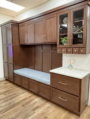Modern kitchen with dark wood cabinets, marble countertop island with sink, stainless steel appliances, and hanging pendant lights.