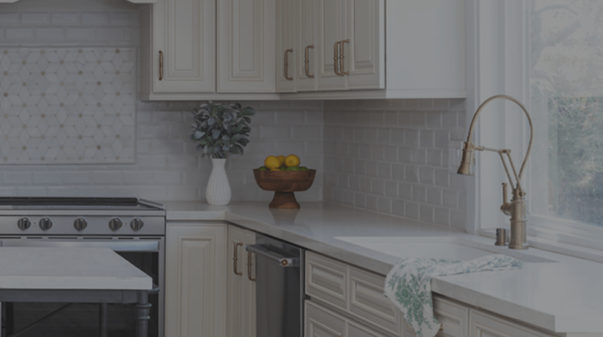 Gray kitchen cabinetry with a built-in wine rack holding three bottles and four hanging wine glasses above a stainless steel faucet and white countertop.