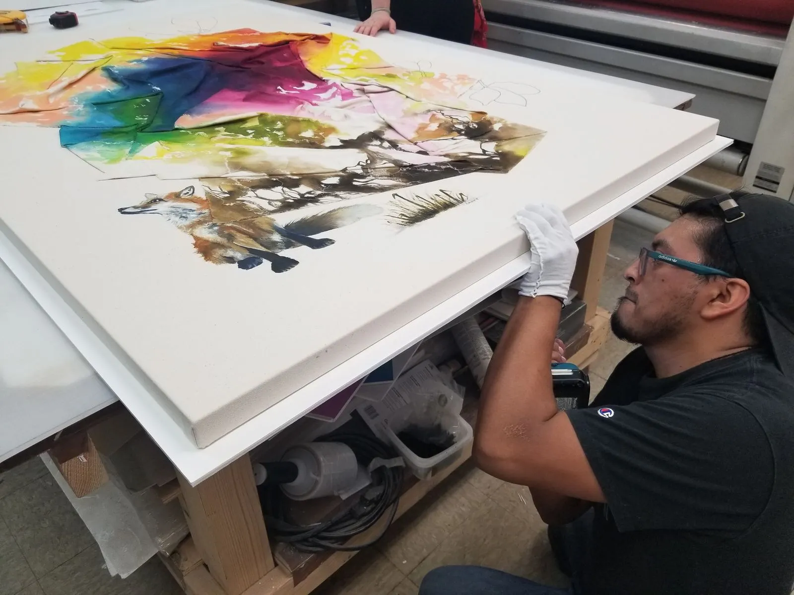 man in production facility handling canvas art to show art curation process