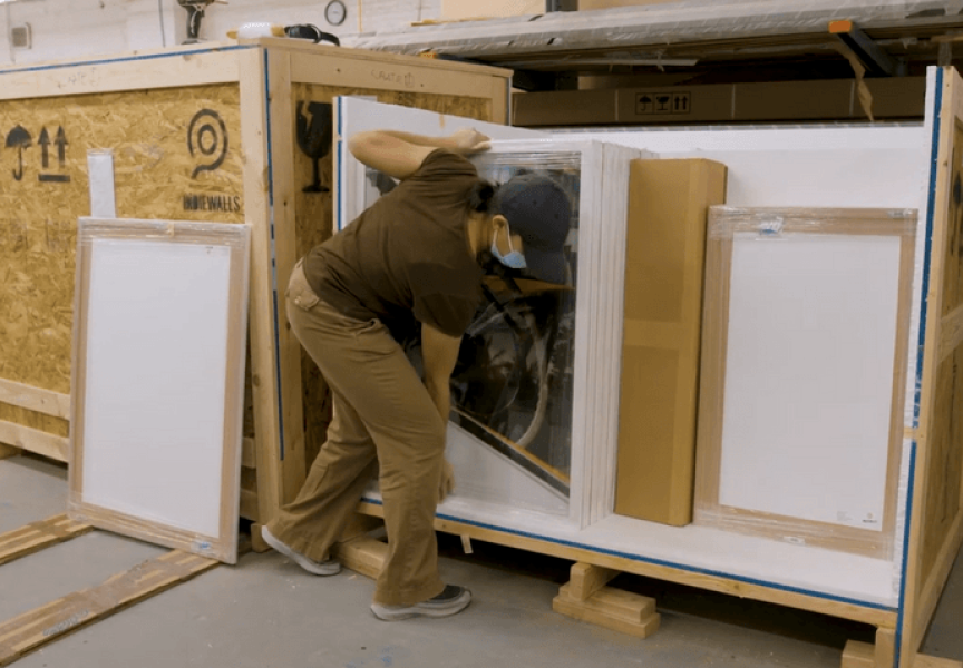 person in production facility packing art to ship