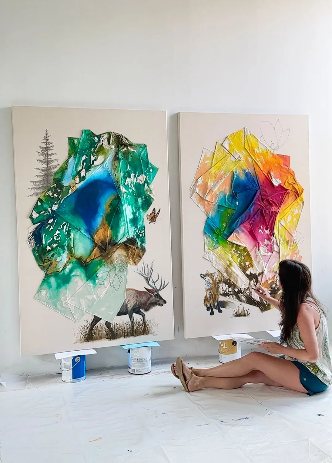 artist in studio sitting painting on two colorful canvases also showing wild forest animals