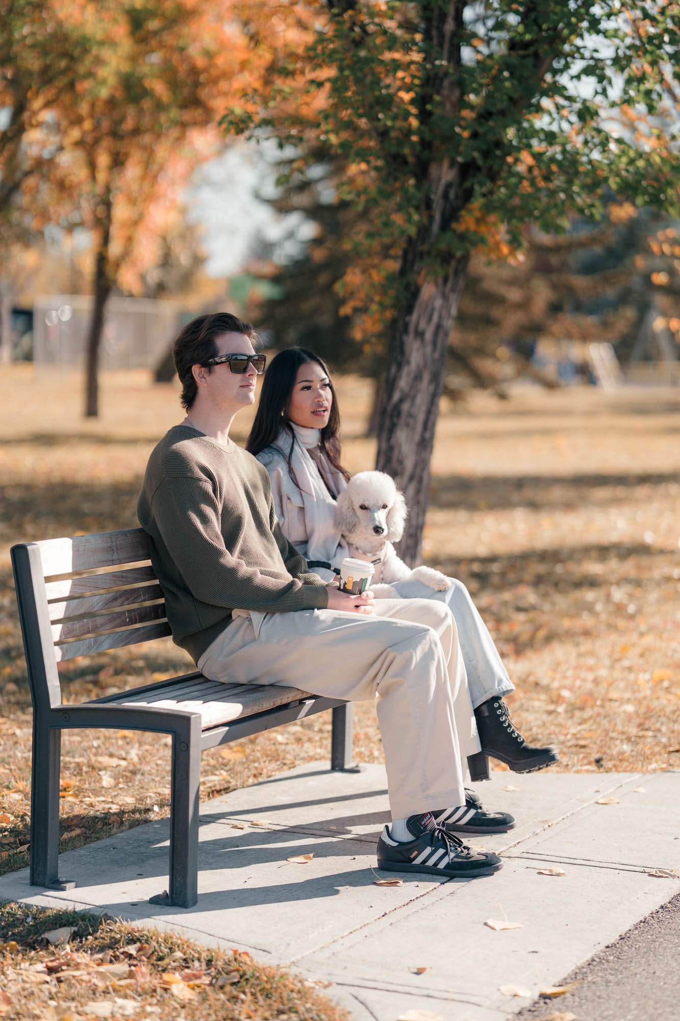 Modern seating area in Munro's Lobby with orange and green chairs, a glass coffee table on a patterned round rug, a wall-mounted fireplace, and wood paneling on ceiling and wall.