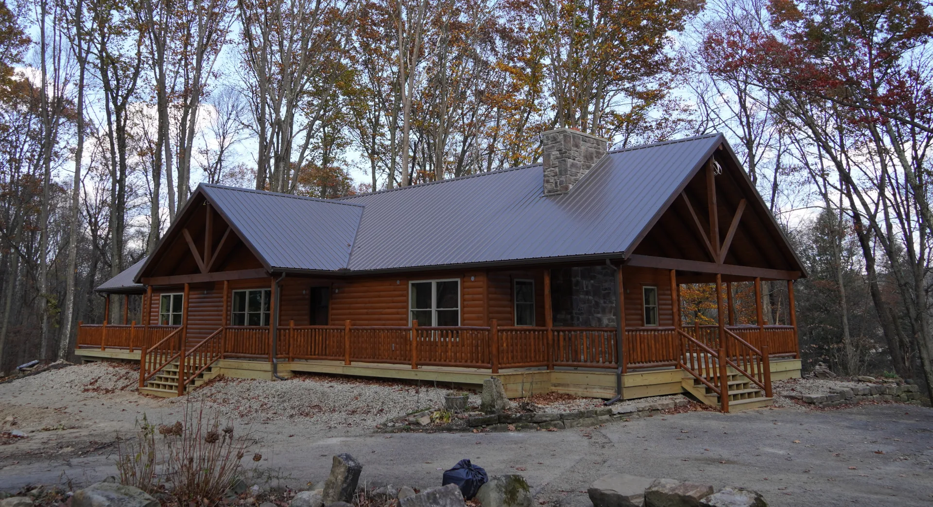 brown modular log cabin home with a metal roof in the woods