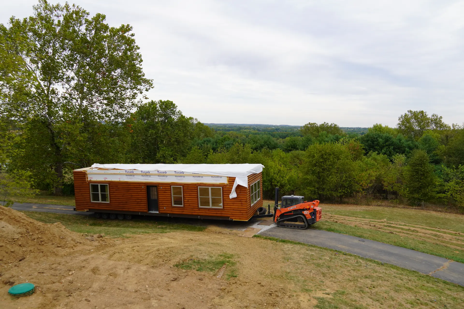 Modular home being delivered and positioned on a rural Ohio property, surrounded by trees and open countryside during the installation process.