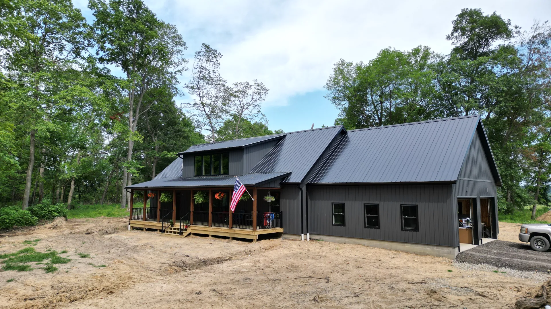 black and grey modular home with front porch, metal roofing, and double gargae doors