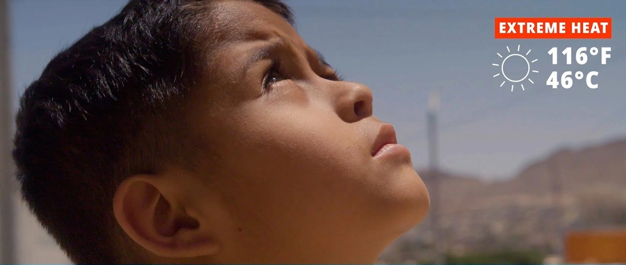 A young boy looks at the sky during heat
