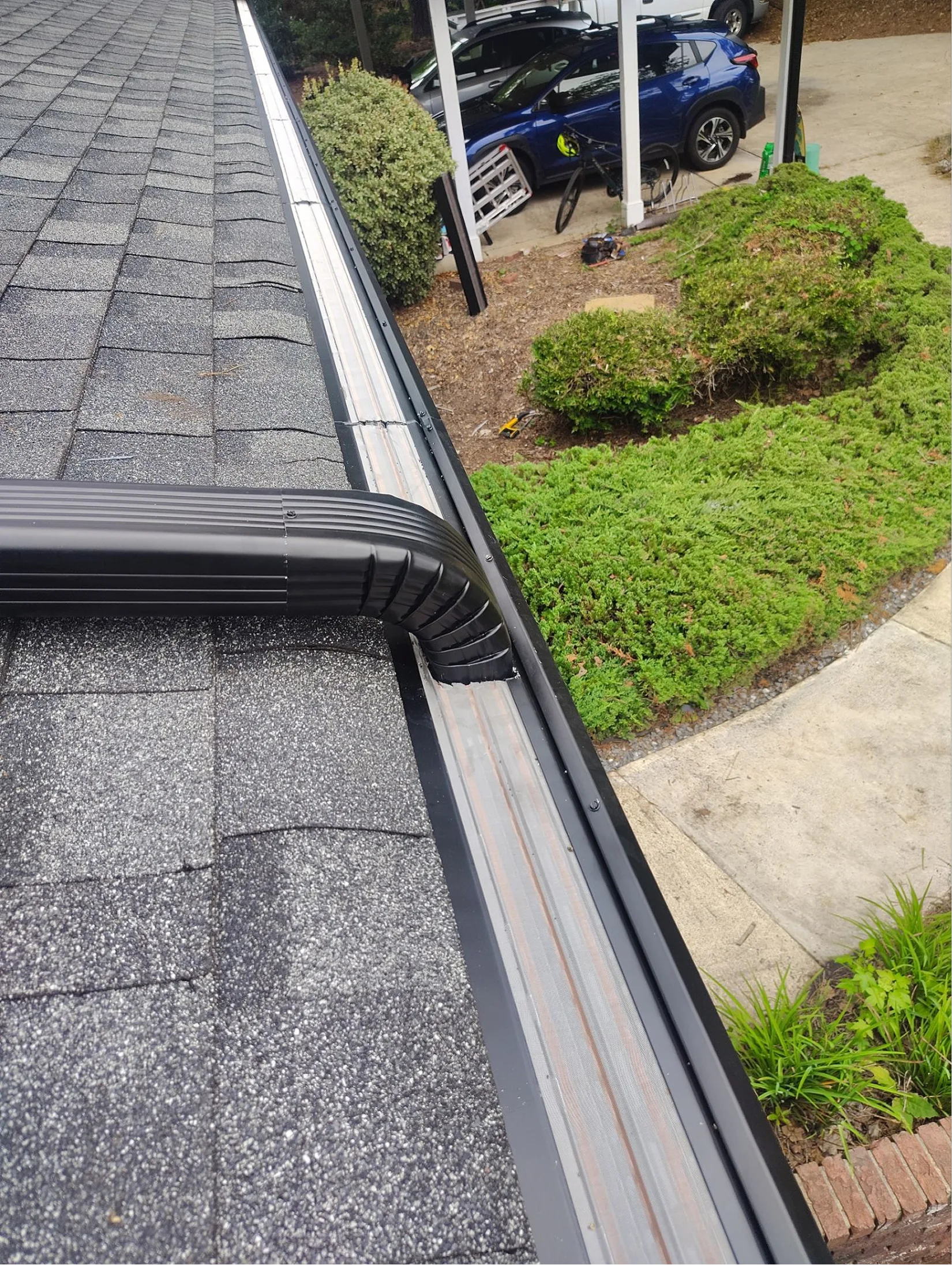 New black aluminum gutter and downspout installed along a residential roof on a home in Raleigh, North Carolina.