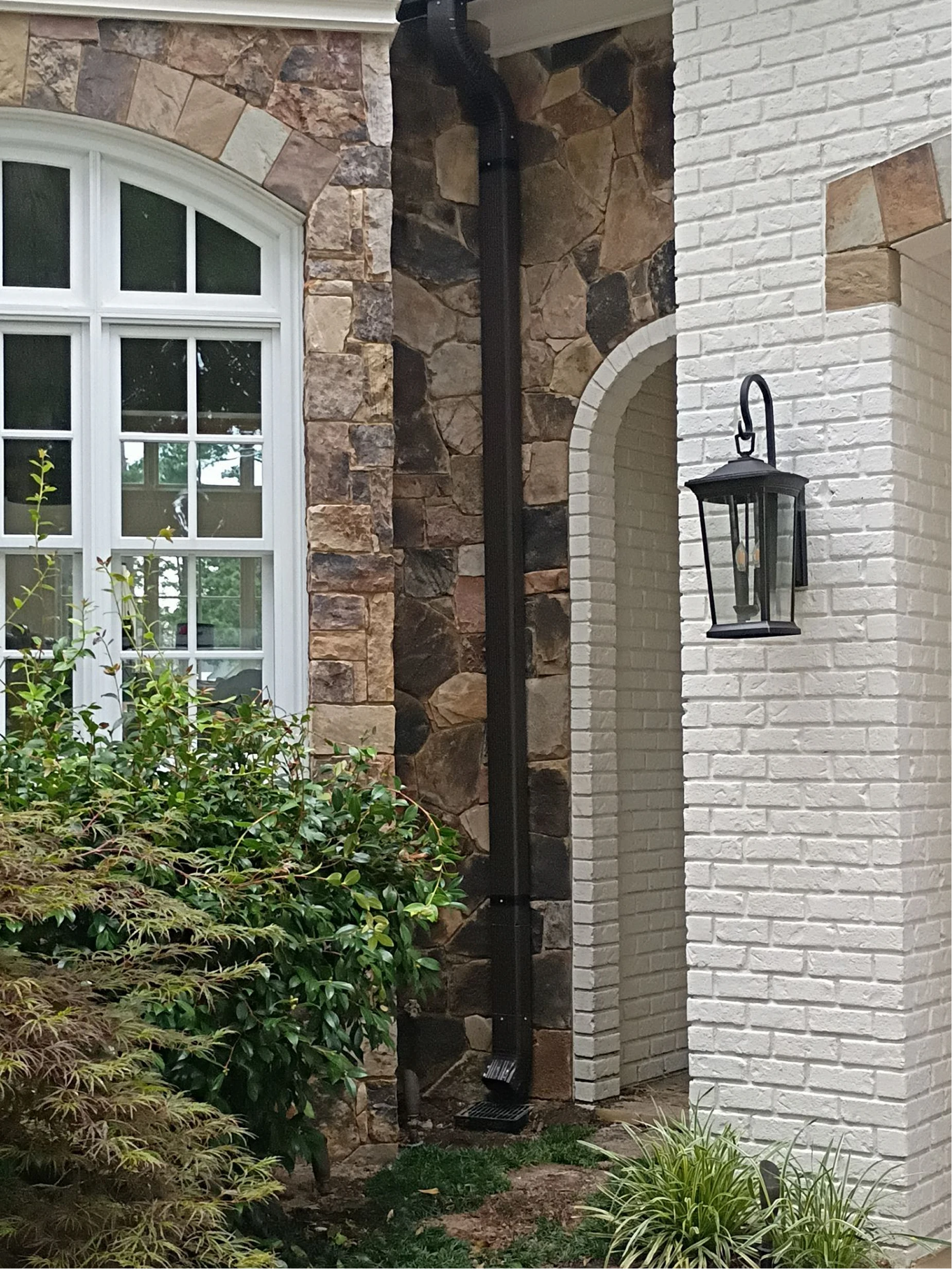 Two technicians installing new gutters on a residential home exterior using ladders during a professional installation project.