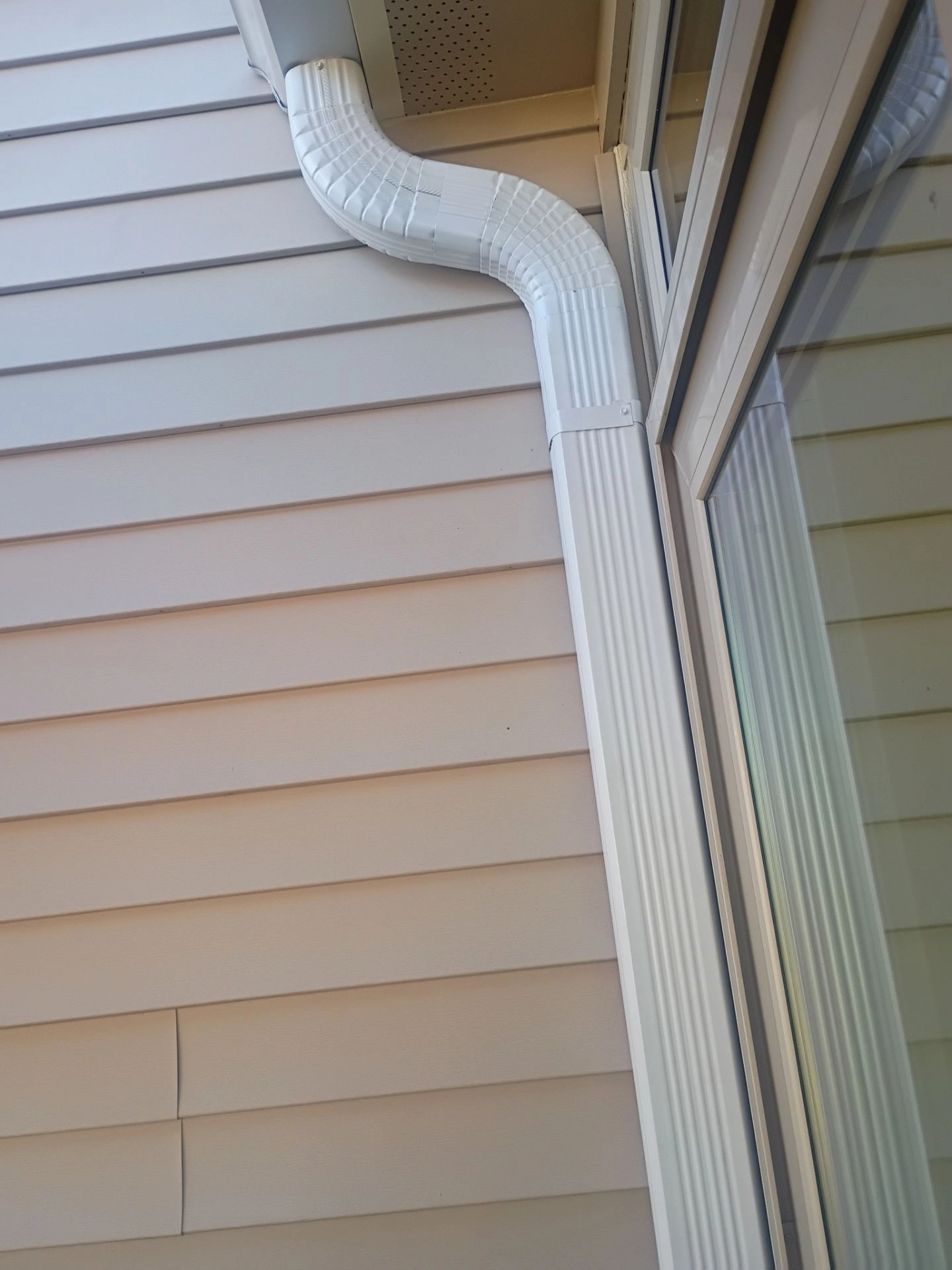 Freshly installed gutter downspout directing rainwater safely away from a residential home exterior.