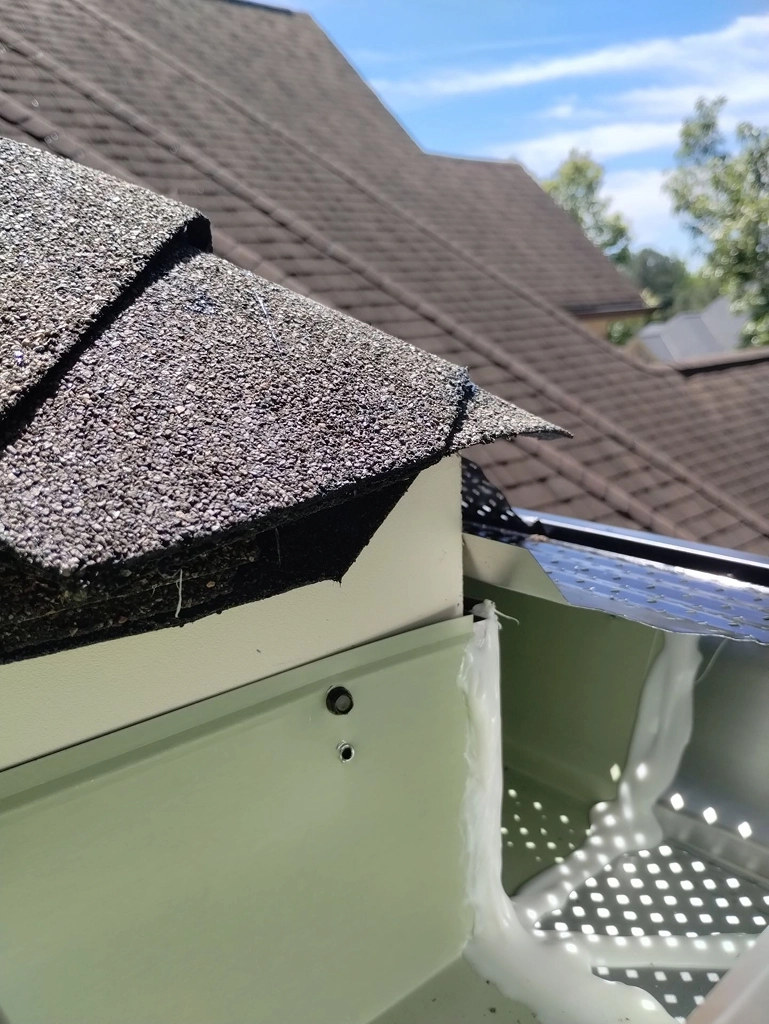 Detailed view of roof shingles and edge work where the roof meets the gutter system.