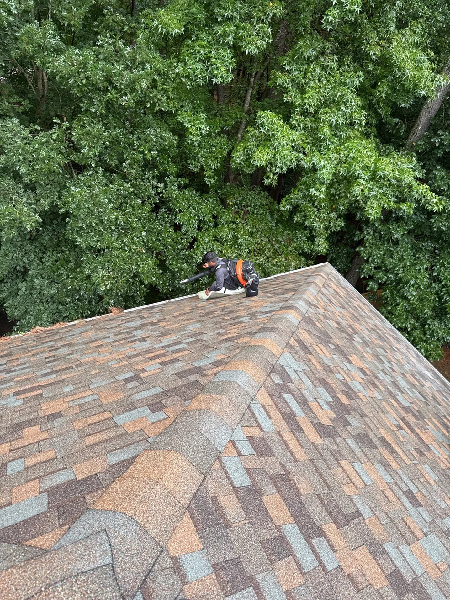 Professional roofer performing roof maintenance and detailing near the roof edge.