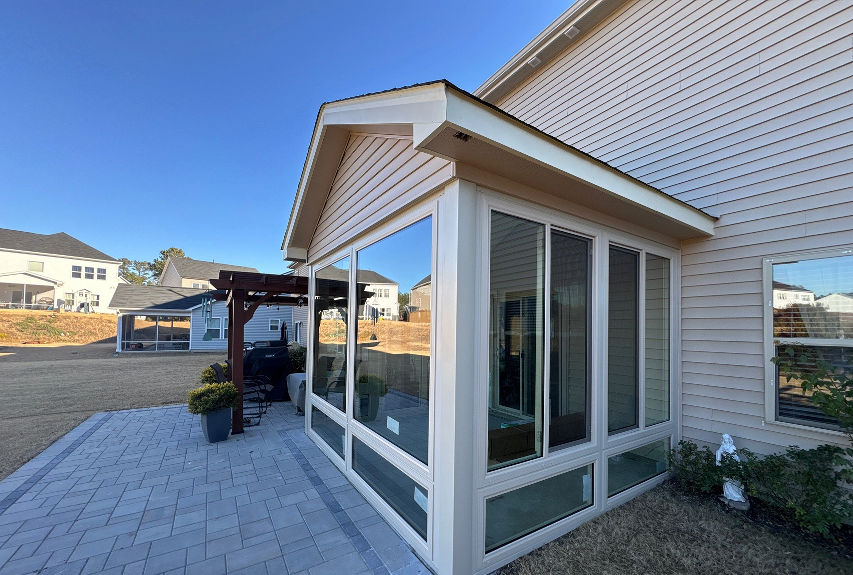 Exterior view of a home featuring a sunroom with siding, trim, and roofline details.