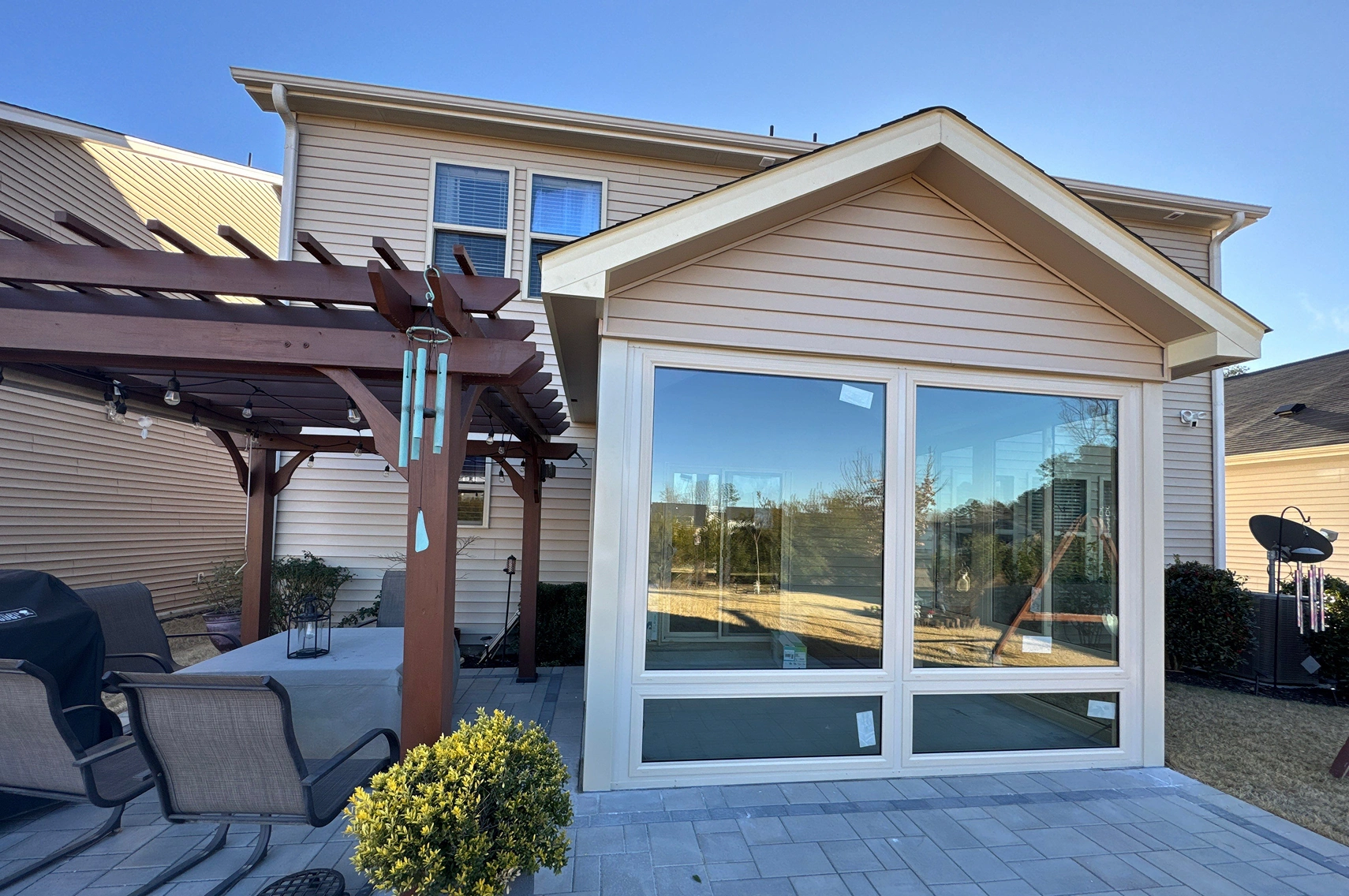 Exterior view of a residential sunroom with large windows, siding, and trim