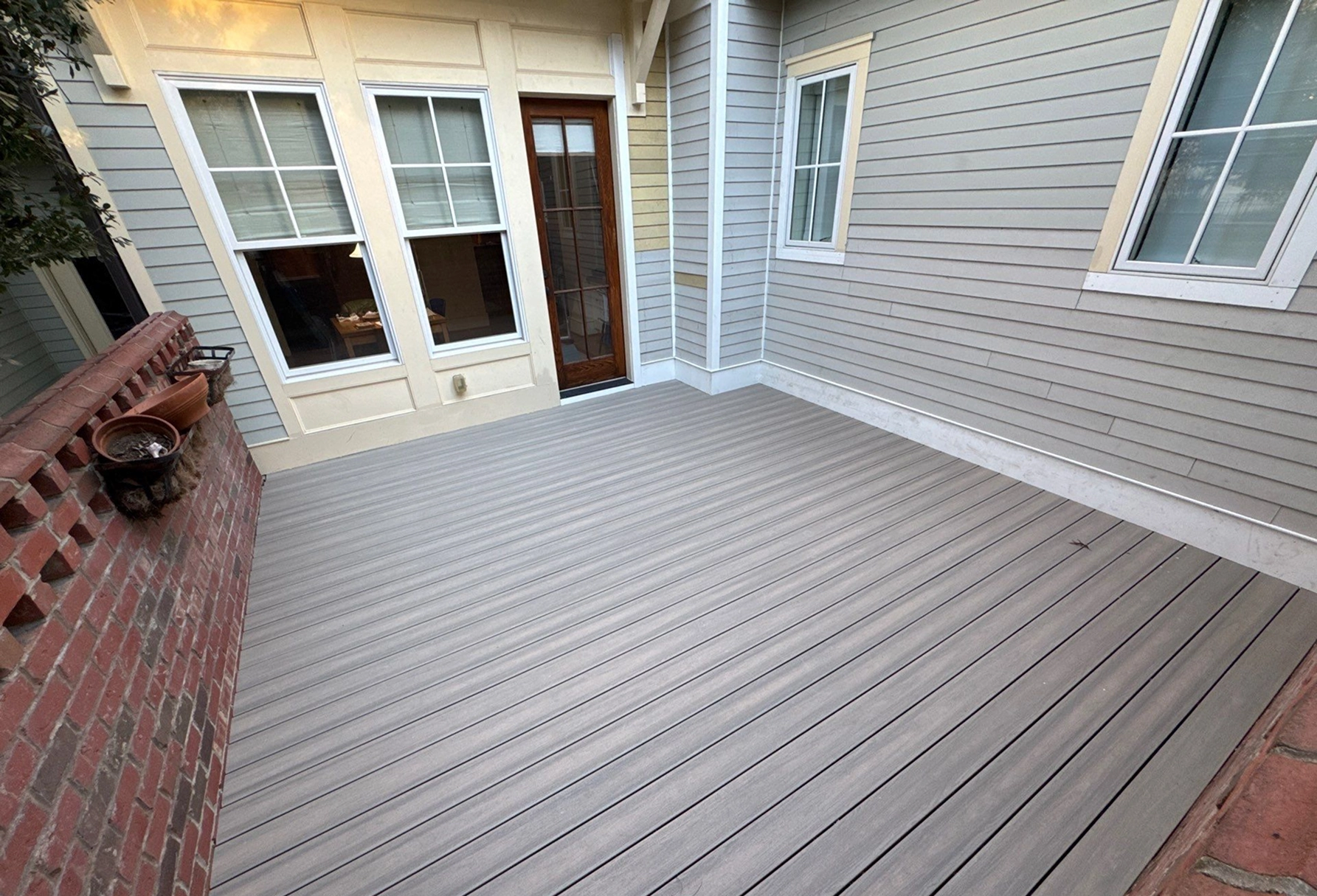 Clean outdoor deck area with gray decking boards next to home exterior.