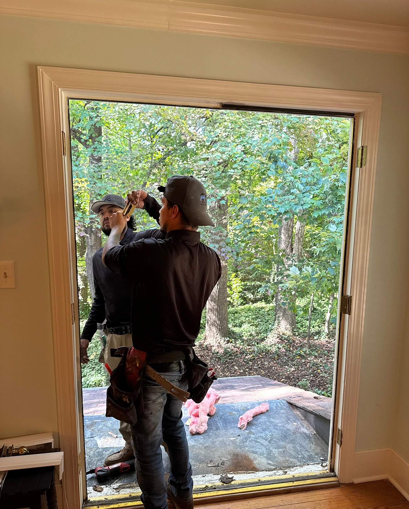Workers fitting a door opening in a residential interior space.