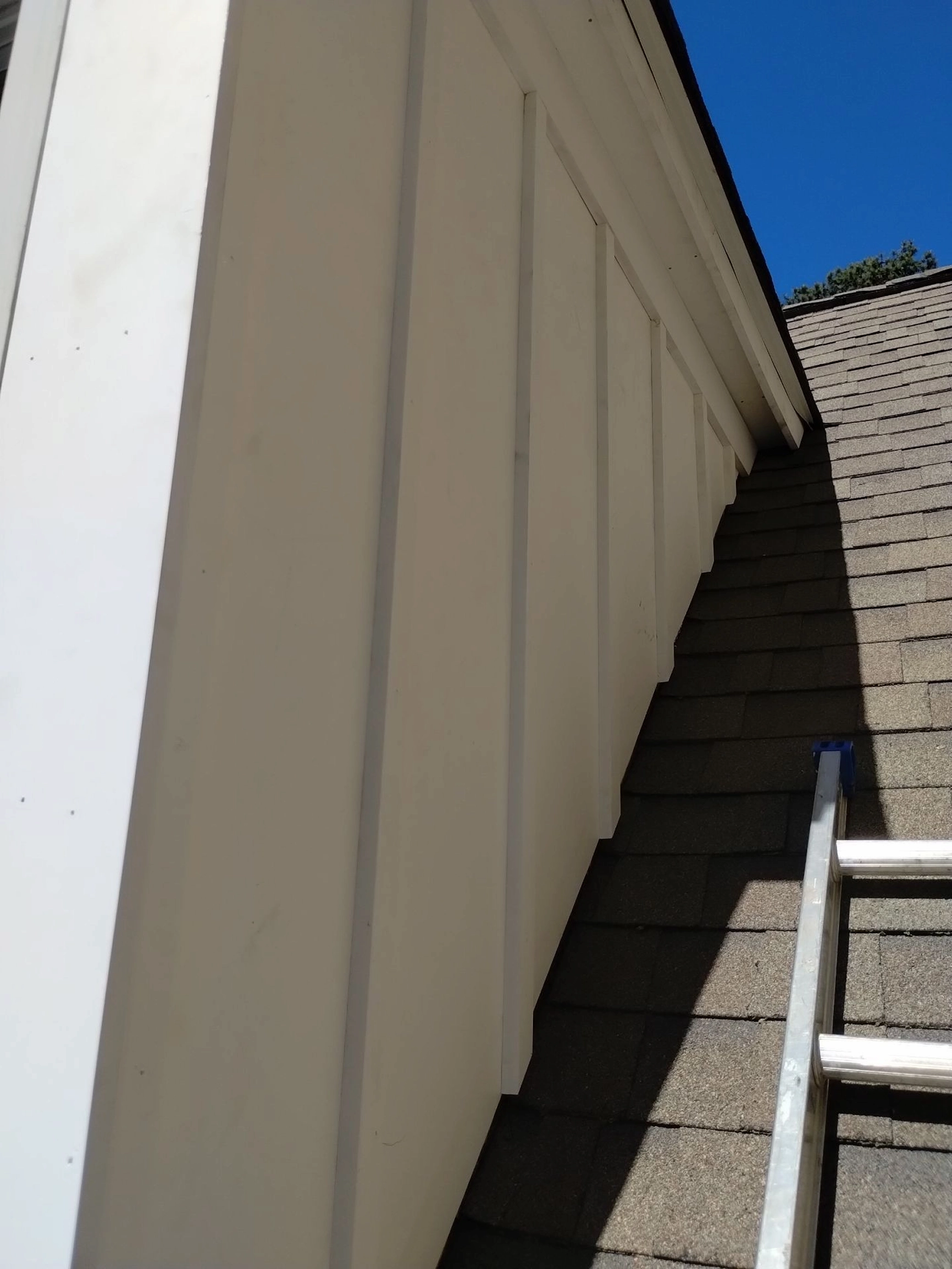 Angled exterior view of upper wall siding and trim near the roof edge of a home.