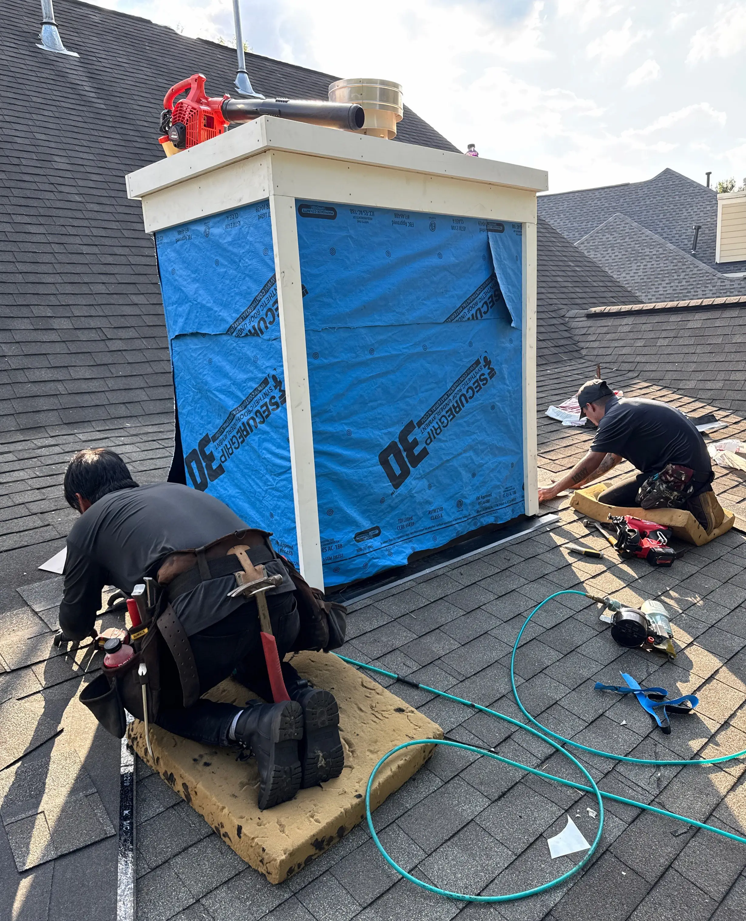 Chimney chase reconstruction in progress, showing new framing, weather barrier, and roof flashing.