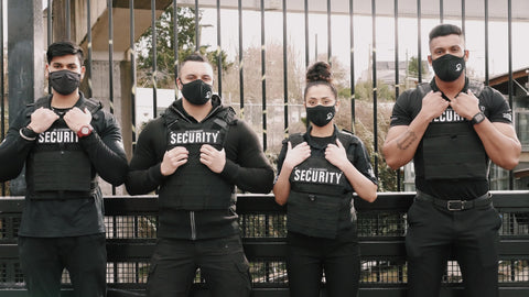 Four Uniformed Blackbird security guards standing in front of fence