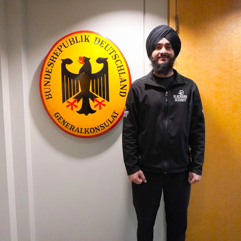 A Blackbird Security guard stands in front of the German Consulate of Canada emblem