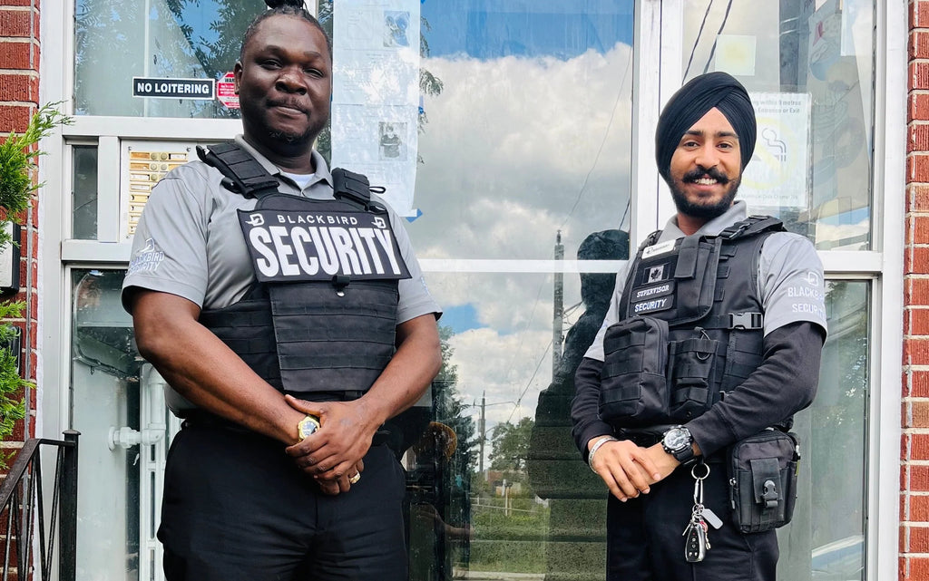 Two Blackbird Security guards stand outside community centre doors.