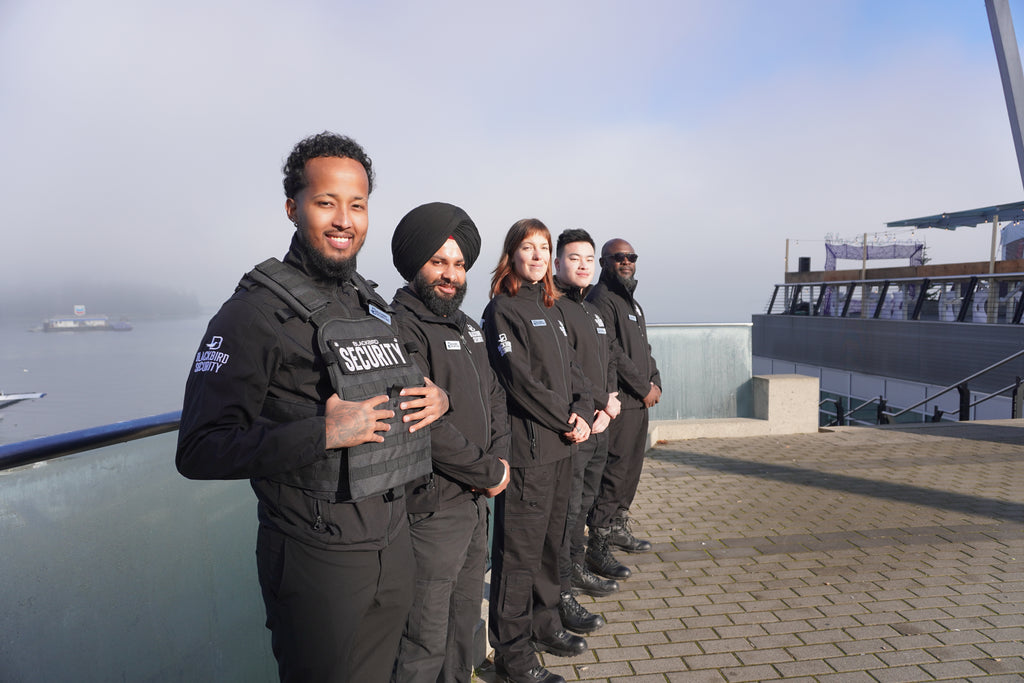Five Blackbird Security guards stand in a row, photographed from a three-quarter angle outside the Vancouver Convention Centre.