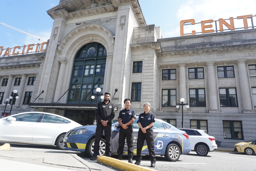 Three Uniformed Blackbird security guard in front of Mobile patrol car at Pacific Centre Transit station