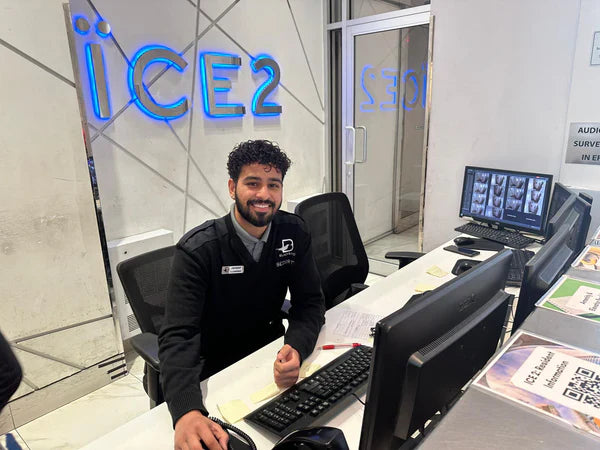 A condo concierge security guard smiles for the camera while seated at a front desk