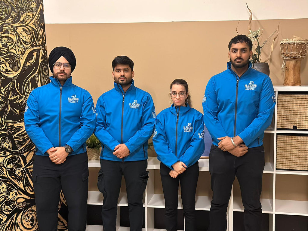 Four Uniformed Blackbird security guards in front of bookcase