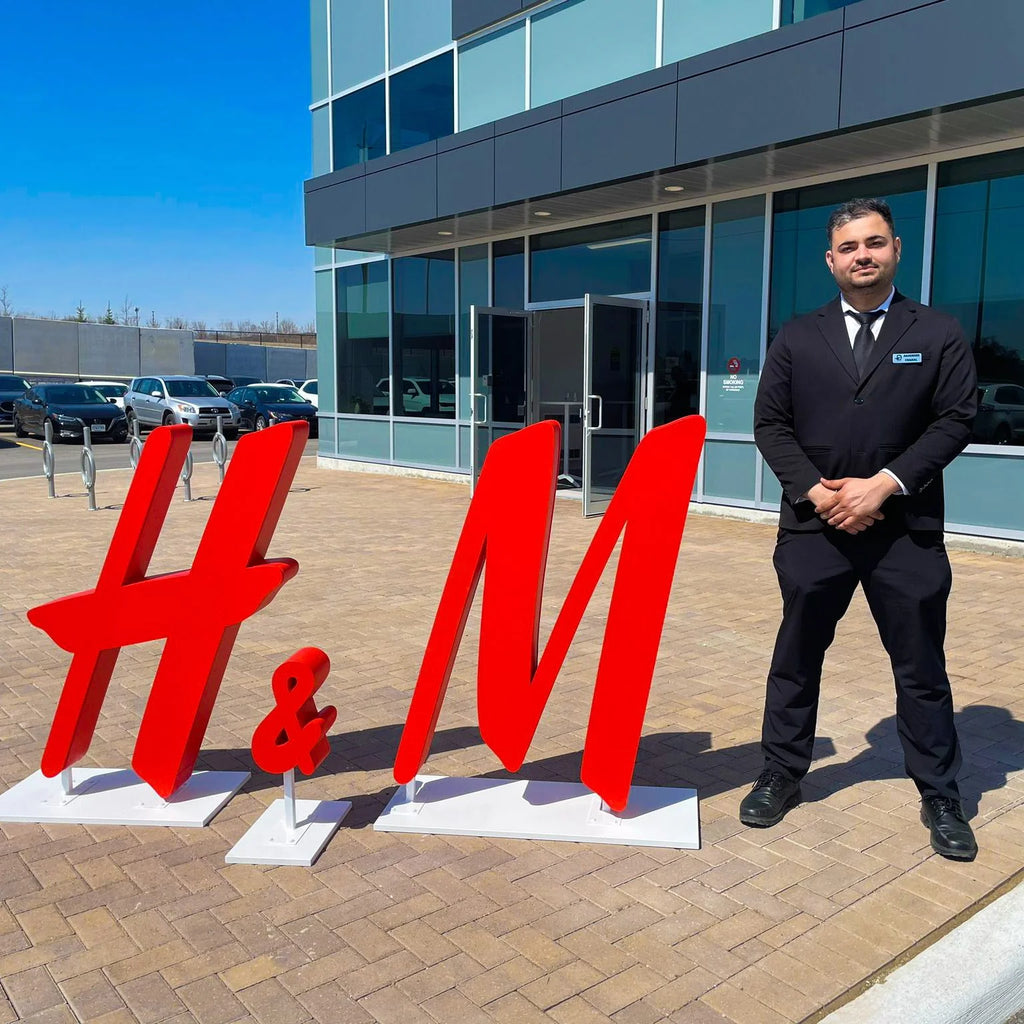 A Blackbird Security guard stands in front of a statue of the H&M logo.