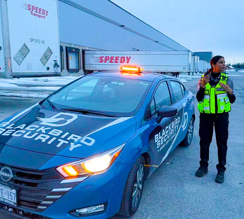 Uniformed Blackbird security guard in front of Mobile patrol car