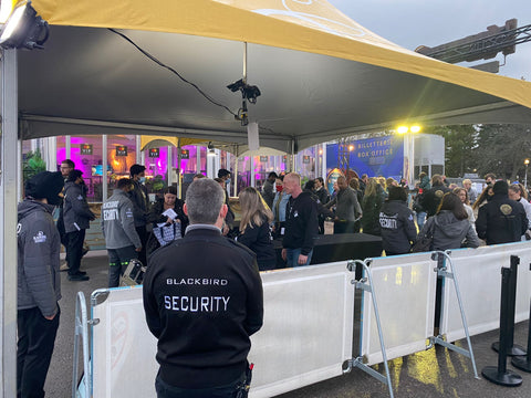 Uniformed Blackbird security guards standing in front of event security fence