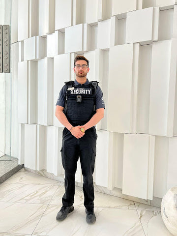 Uniformed Blackbird security guard standing in front of building