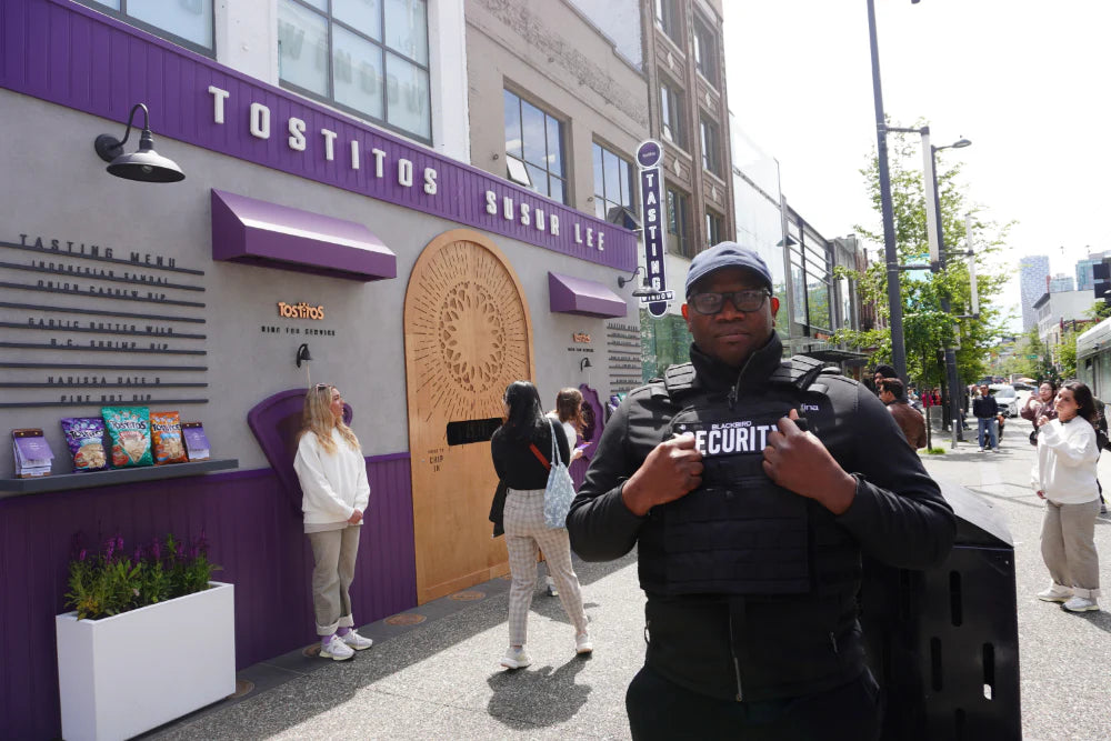 A Blackbird Security guard stands on a Vancouver street in front of the Tostitos Window Event popup building