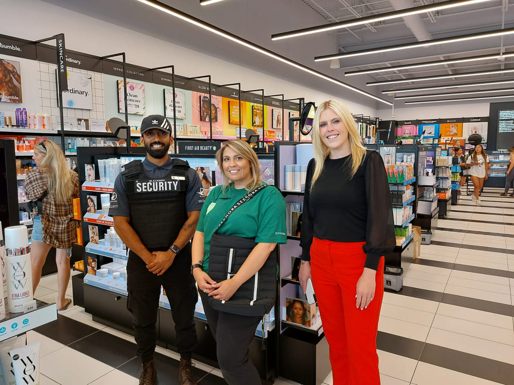 Blackbird security guard standing in retail location with two women