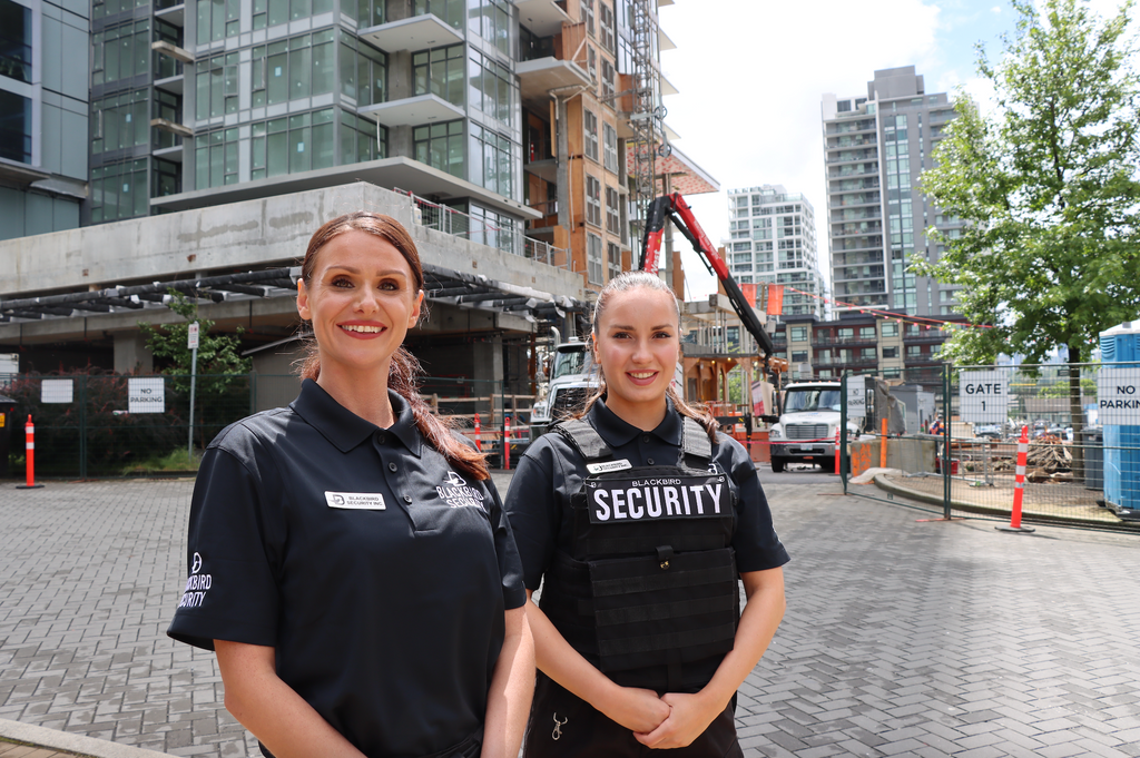 Two female security guards stand facing the camera.