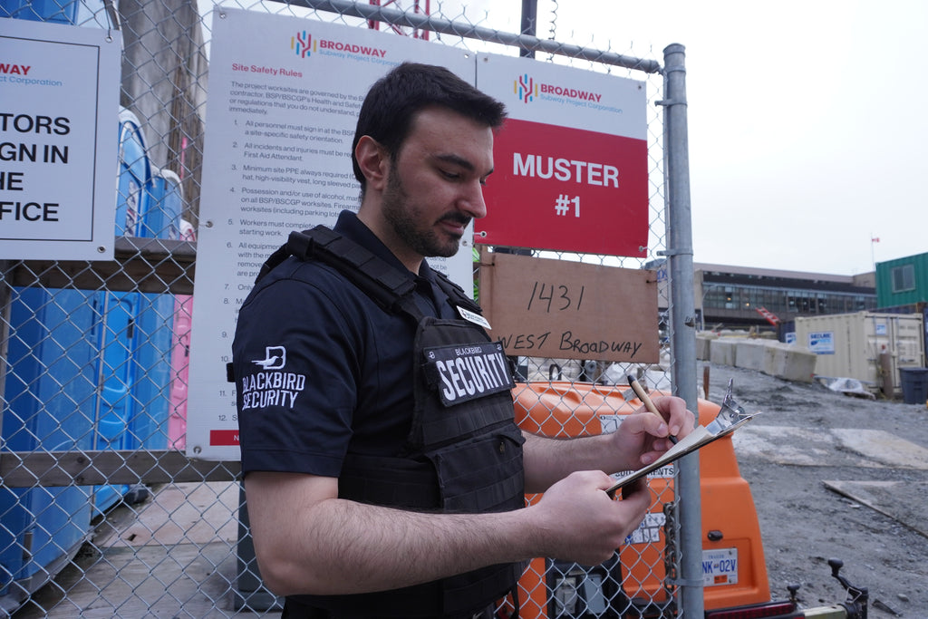 A construction site security guard writes notes on a clipboard.