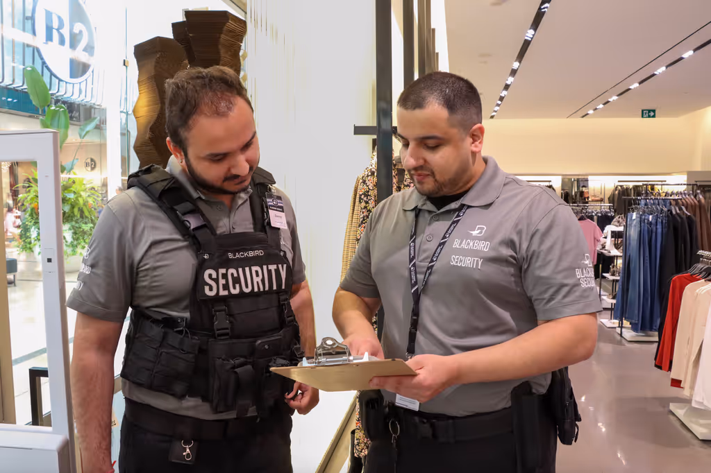 Two loss prevention guards (LPOs) look at a clipboard together inside a store.