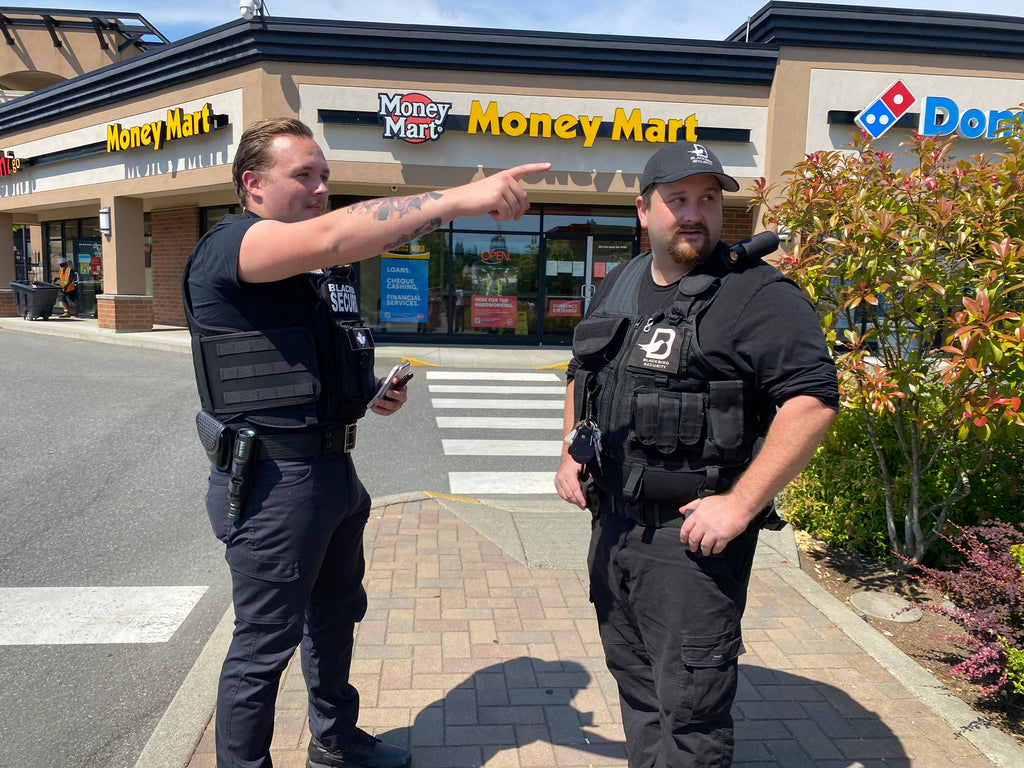 Two Blackbird security guards standing in strip-mall parking lot