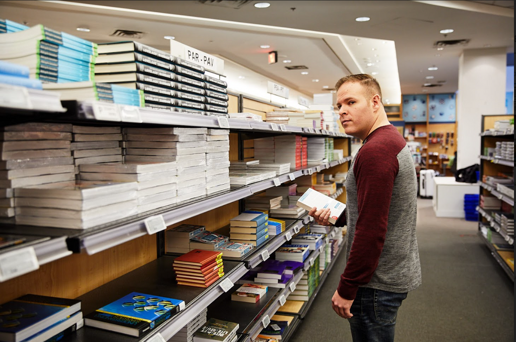 A loss prevention operative looking at a book in a bookstore aisle