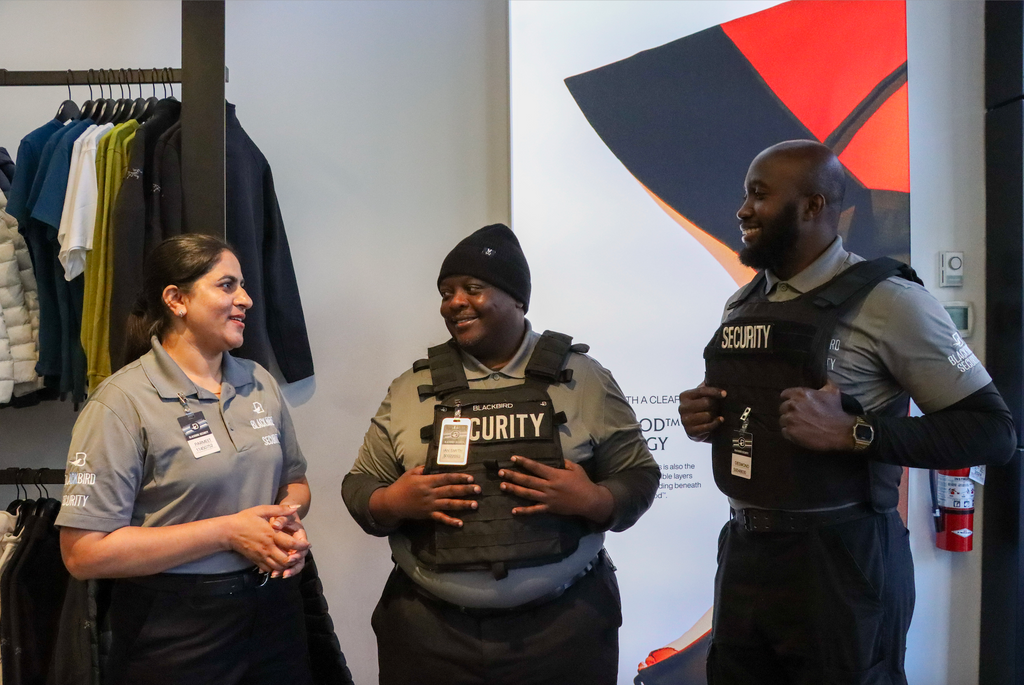 Three security guards discuss together inside a store.