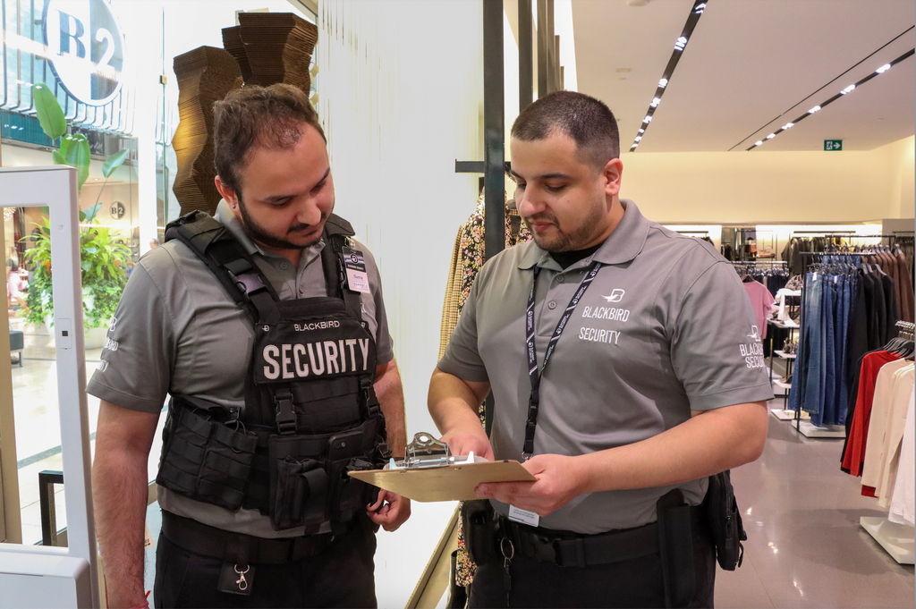 Two retail security guards look at a checklist inside a store