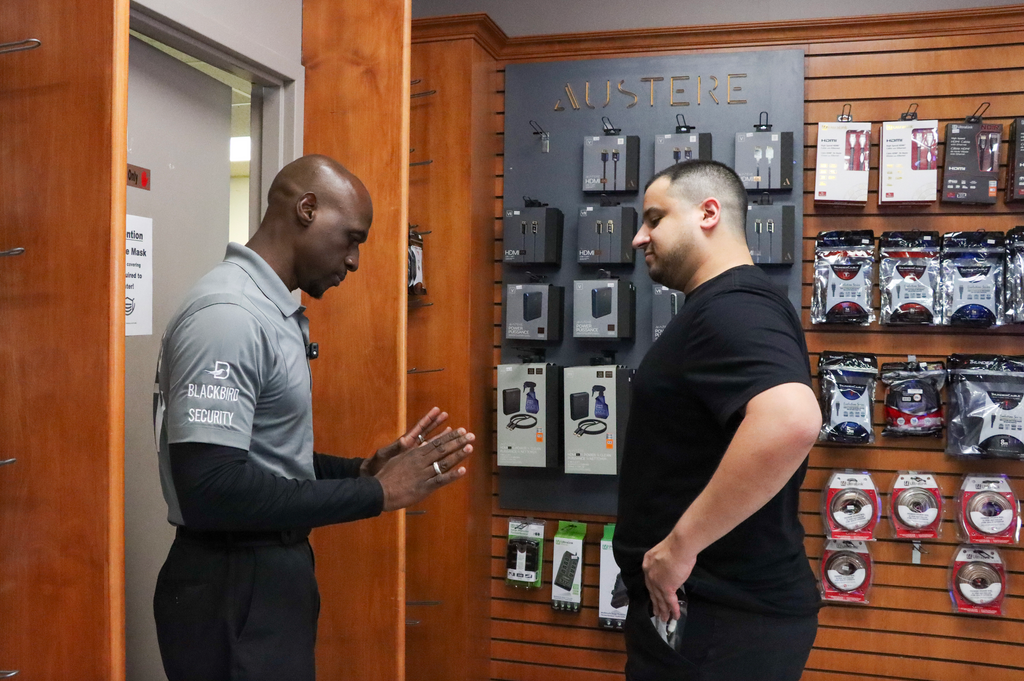 A security guard stops a subject in a store.