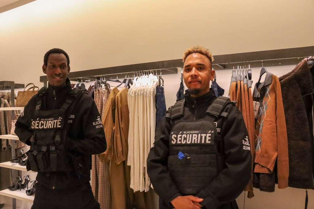 Two retail security guards wearing vests inside a clothing store.