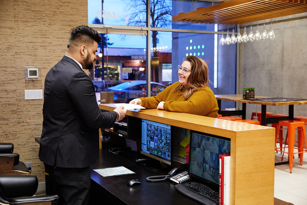 Concierge guard assisting a woman at a front desk.