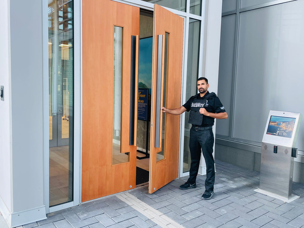 Condominium security guard holding a large lobby entrance door open