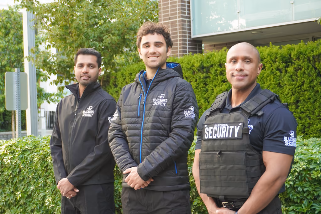 Three residential security guards stand outside of a housing community