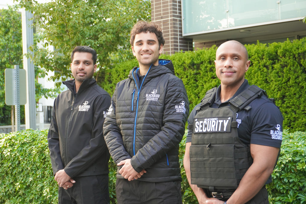 Three residential security guards stand outside of a housing community