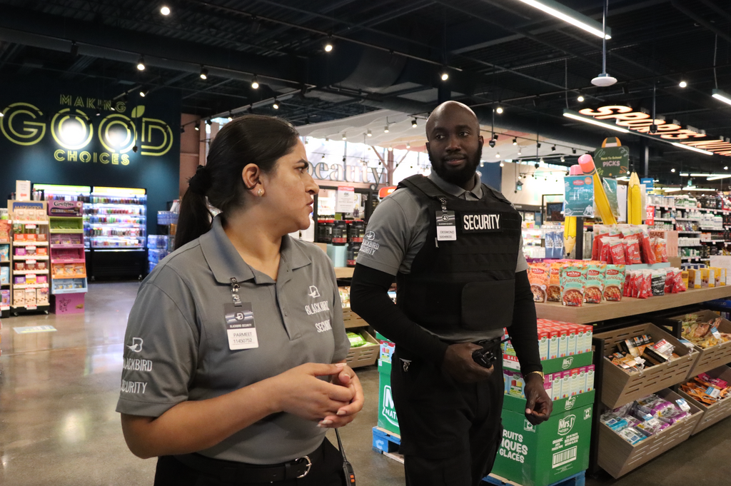 Two retail security guards walk through a grocery store.