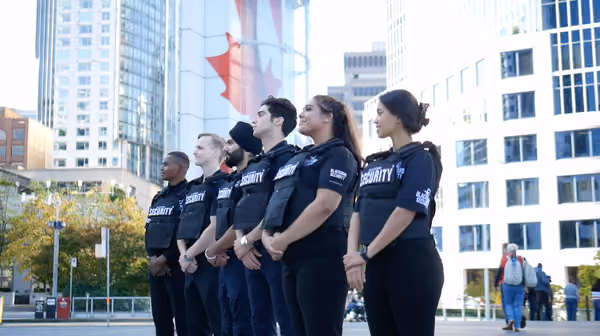 Five Blackbird security guards standing in a row looking out over street
