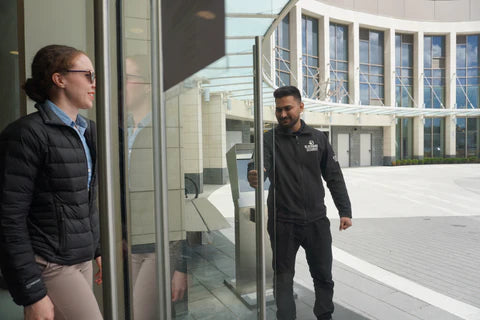 A Blackbird Security guard opens a condominium lobby door for a woman